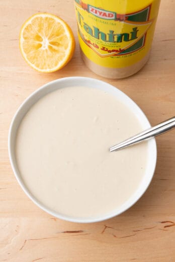 Tahini sauce in a large bowl with juiced lemons