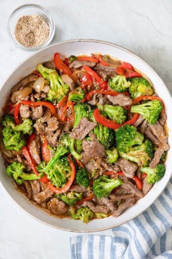 Overhead shot of teriyaki beef stir fry in a large skillet garnished with sesame seeds.