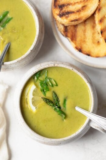 Close up of cream of asparagus soup in bowl with spoon