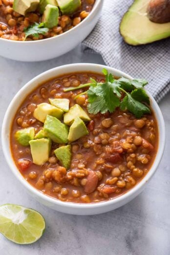 Two bowls of vegan lentil chili with avocado